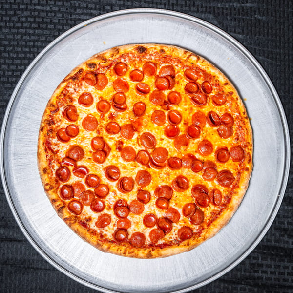 Delicious pepperoni pizza with melted cheese on a round metal pan, on a dark tablecloth.