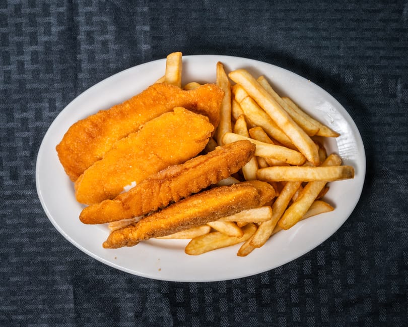 Golden fried chicken tenders and crispy french fries served on a white plate.