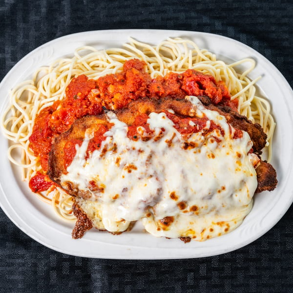 Spaghetti with chicken parmesan covered in melted cheese and red sauce on a white plate.