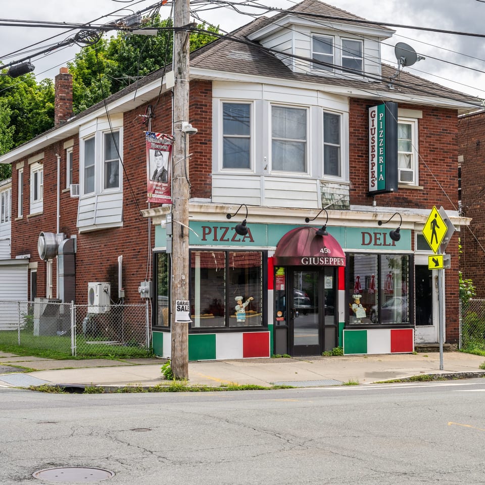 Giuseppe's Pizzeria & Deli on a street corner, with Italian flag colors on its facade.